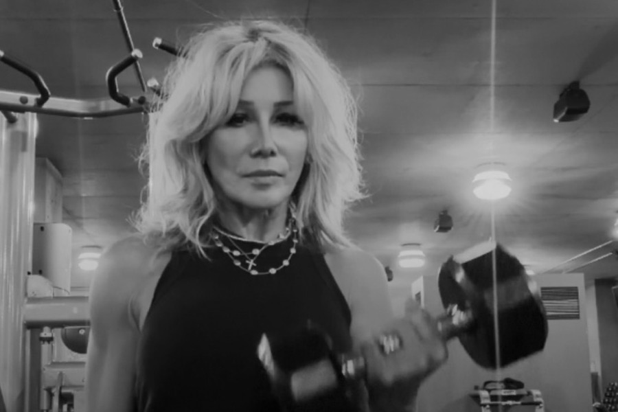 Kim Fisher curling a dumbbell at the gym, in black and white